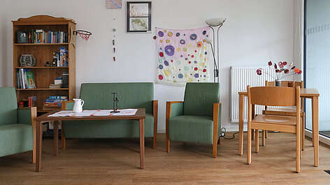 Wohnzimmer mit Bücherregal und Sitzgruppe