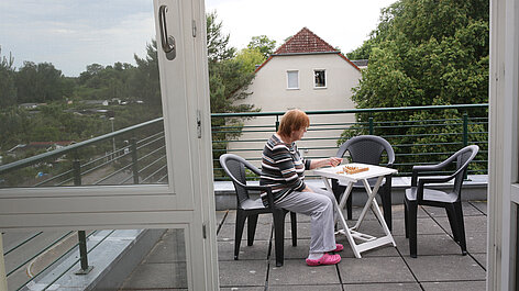 Frau sitzt am Tisch auf der Terrasse