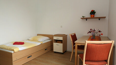 Kleines Zimmer mit Bett und Tisch