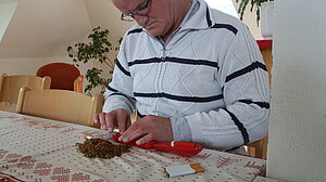 Mann stopft Zigaretten am Tisch