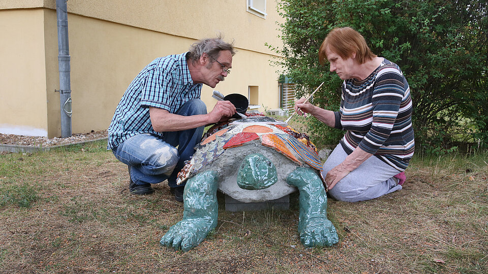 Zwei Personen bemalen eine Schildkröte