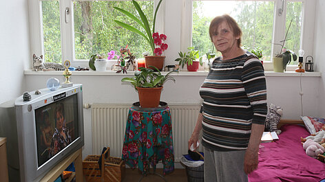 Frau in Zimmer mit vielen Zimmerpflanzen