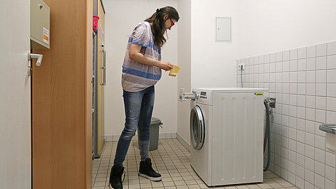 Person lädt Waschmittel in Waschmaschine