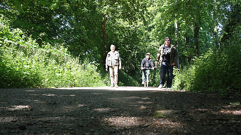 Drei Personen auf Waldweg
