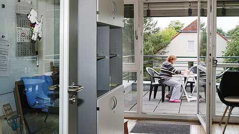 Person sitzt am Tisch auf Balkon