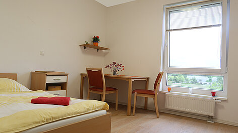 Helles Zimmer mit Bett und Schreibtisch