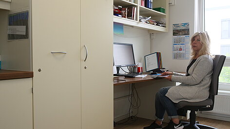 Frau sitzt am Schreibtisch im Büro